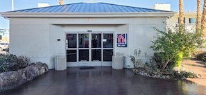 A building with a metal roof, a glass door entrance, and a sign indicating a lobby. - Studio 6 Suites Las Vegas, NV – Tropicana (Las Vegas)