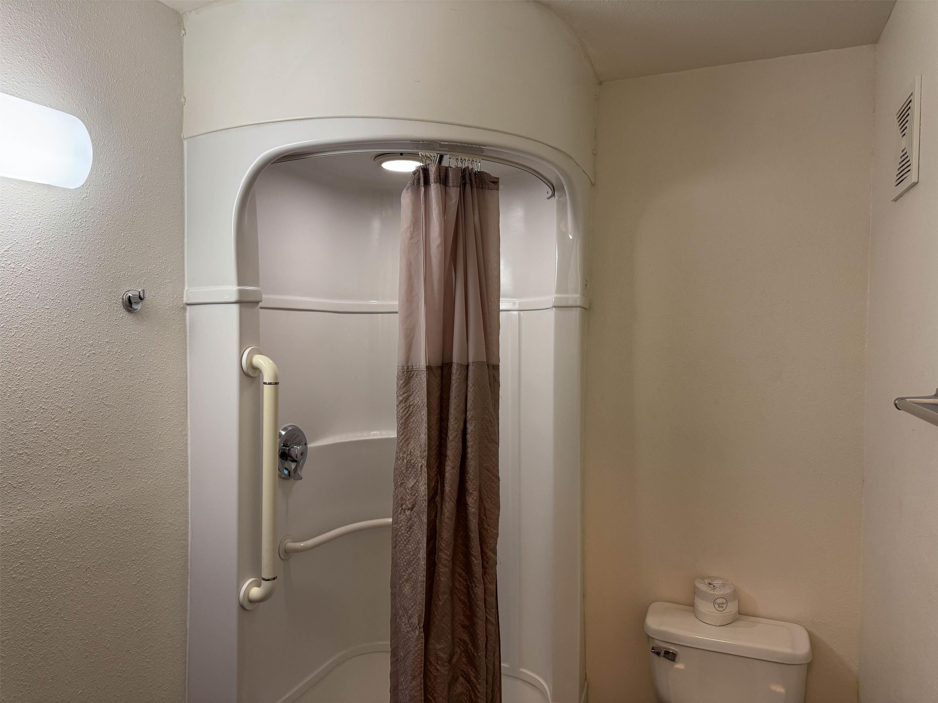 Un baño con cabina de ducha, inodoro y toallero.