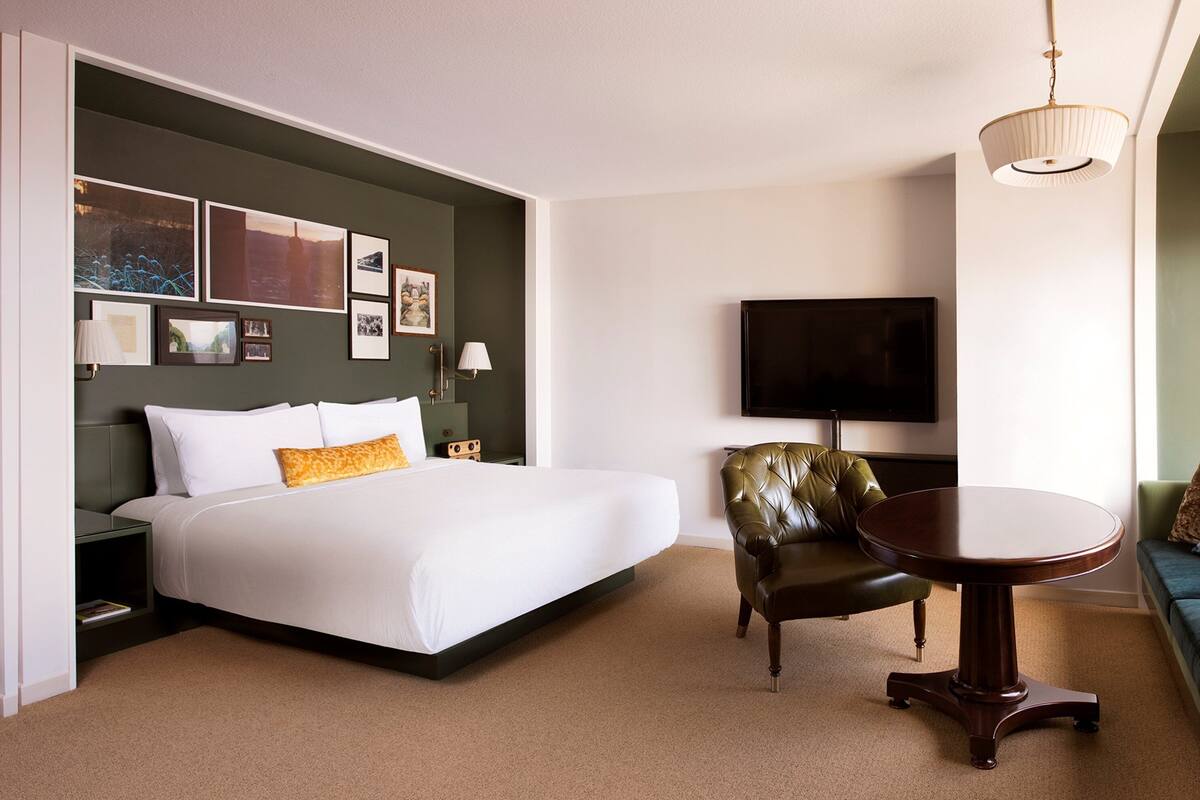 A hotel room with a bed, a television, a sofa, and a dining table.