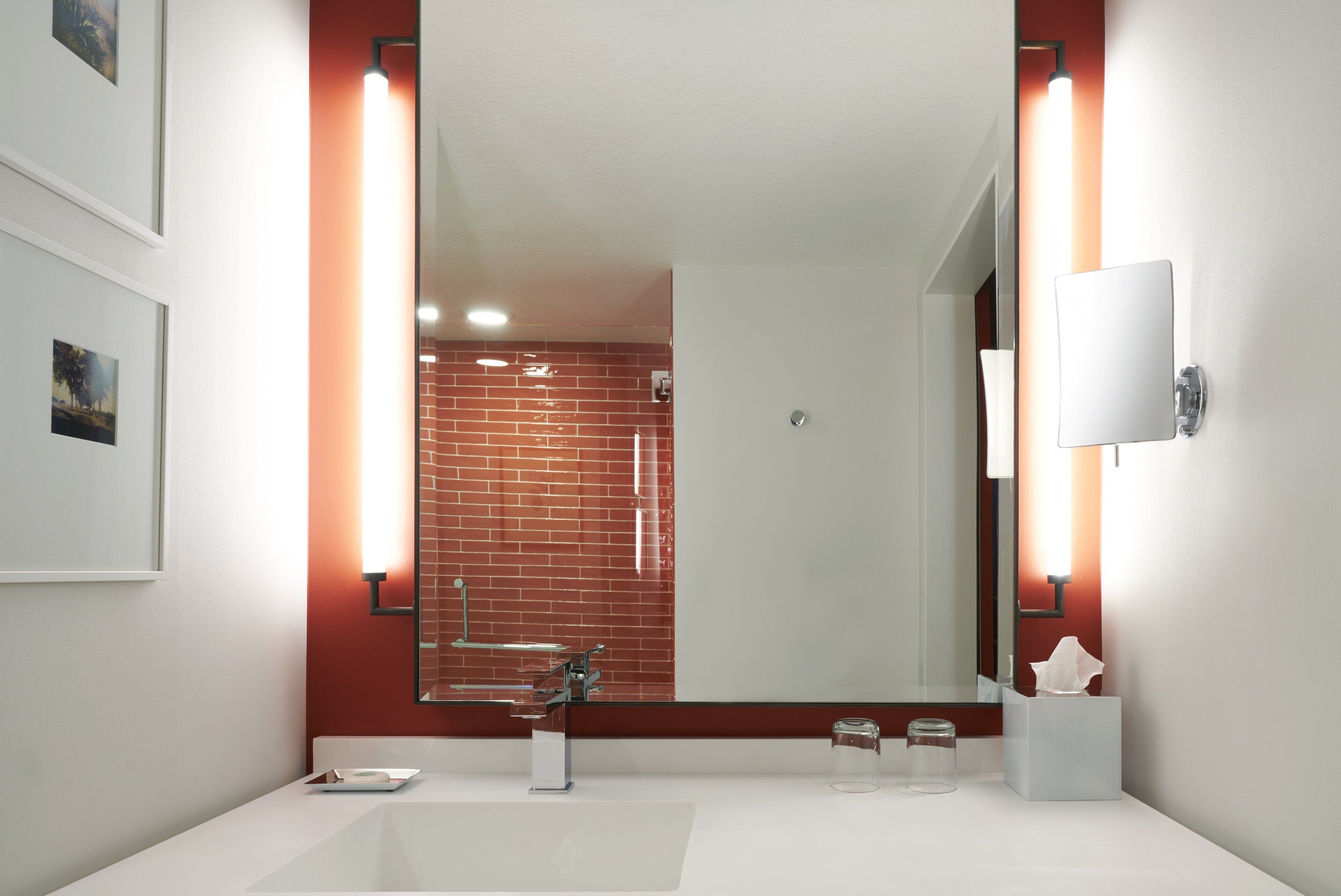 A modern bathroom with a white sink, a glass shower enclosure, and a large mirror.
