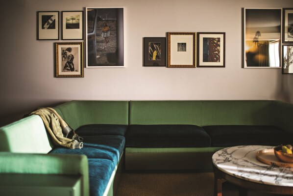 A living room with a green sofa, a round coffee table with a bowl, and framed artwork on the wall. - Park MGM Las Vegas (Las Vegas)