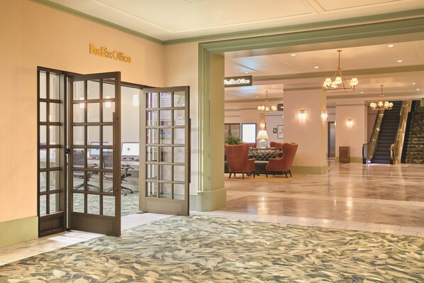 A FedEx Office lobby with a reception desk, seating area, and an escalator. - Park MGM Las Vegas (Las Vegas)