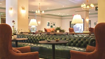 A green leather sofa with a round table in the center, surrounded by brown leather armchairs.