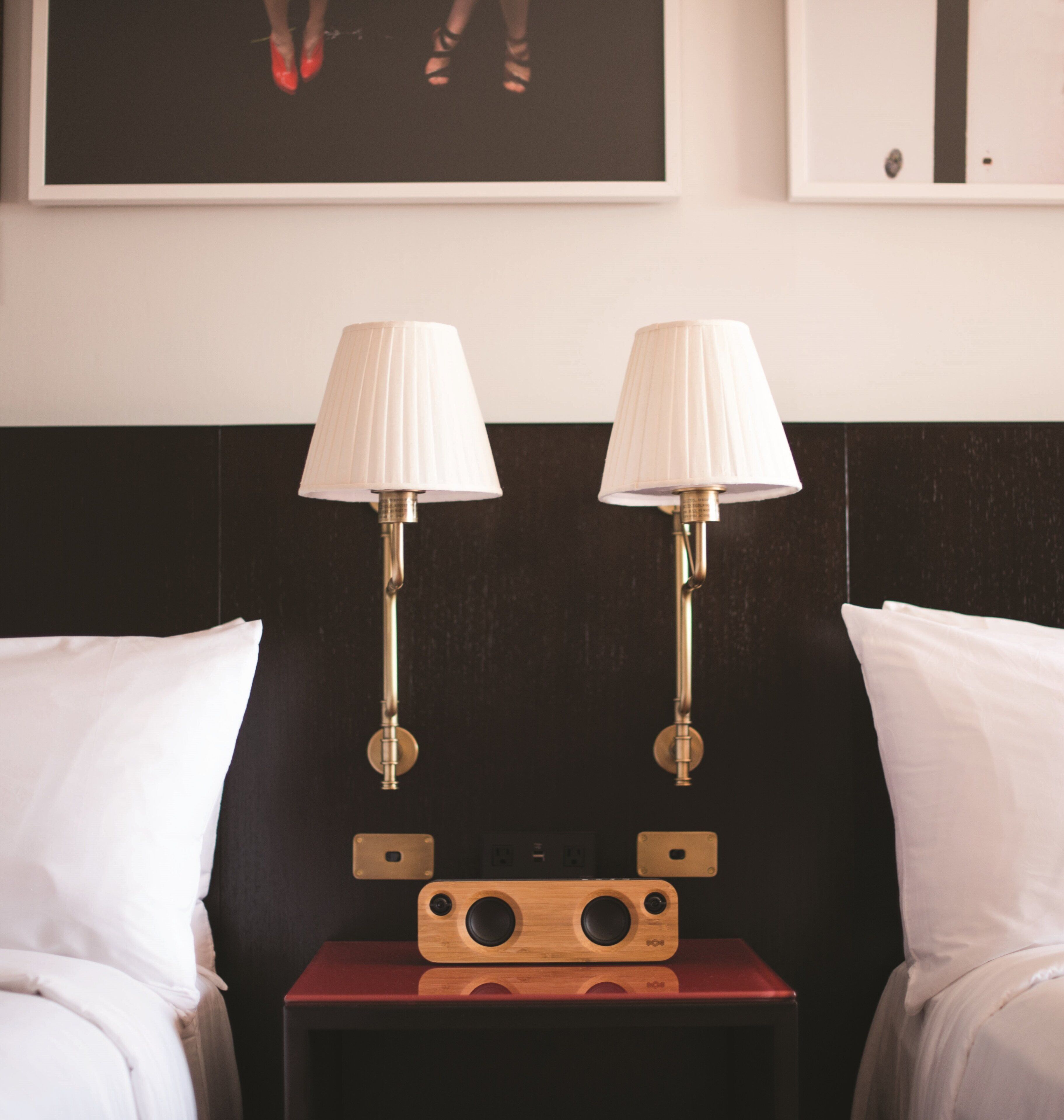 Una camera d'hotel con due comodini, ognuno dotato di lampada e cassa in legno.