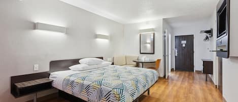 A modern hotel room with a bed, bedside table, and a small desk area.