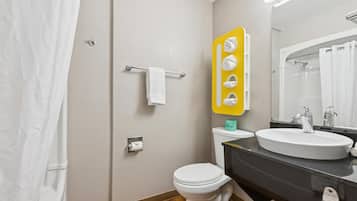 A bathroom with a white toilet, a sink with a mirror above it, and a shower area.