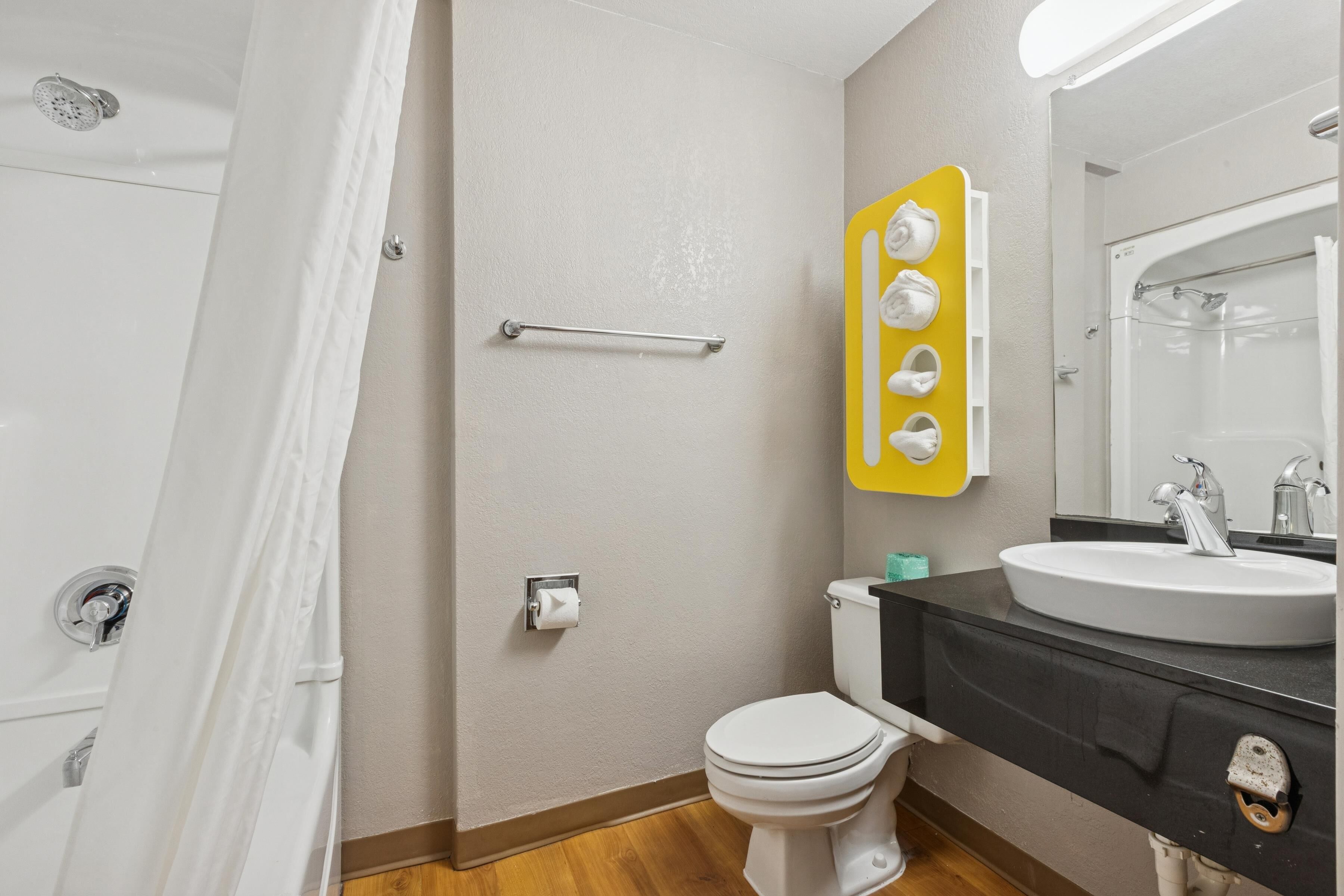Et badeværelse med bruser, toilet, vask og håndklædeholder.
