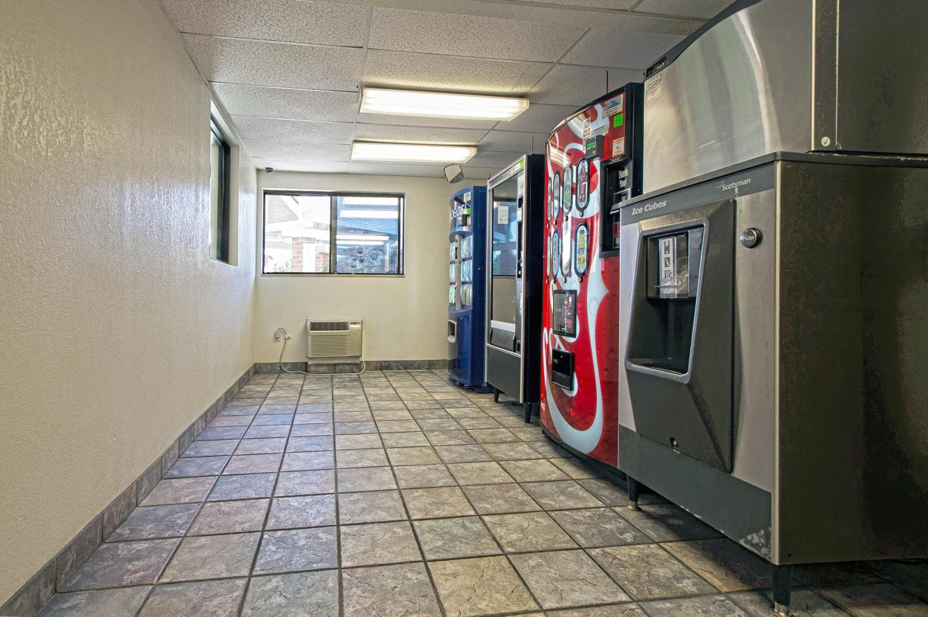 A hallway with vending machines, a window, and a tiled floor.