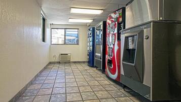 A hallway with vending machines, a window, and a tiled floor.