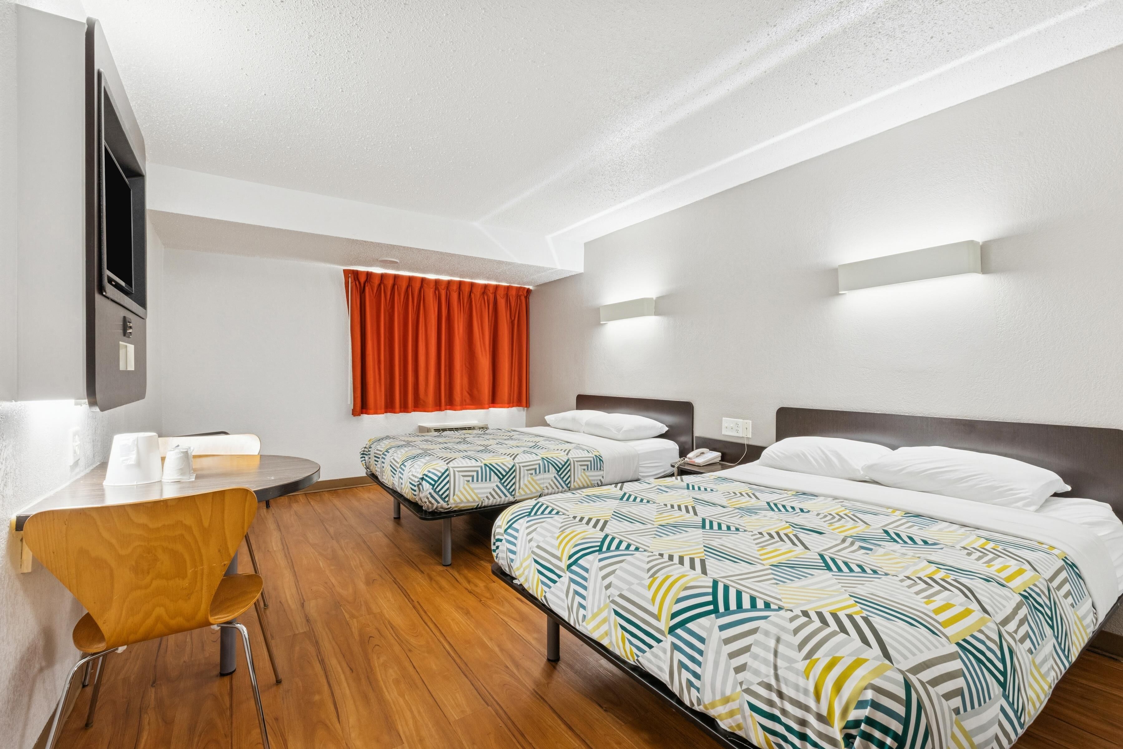 Una habitación de hotel con dos camas, un escritorio y una silla.