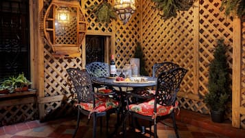 A dining area with a round table, four chairs, and a bottle of wine.