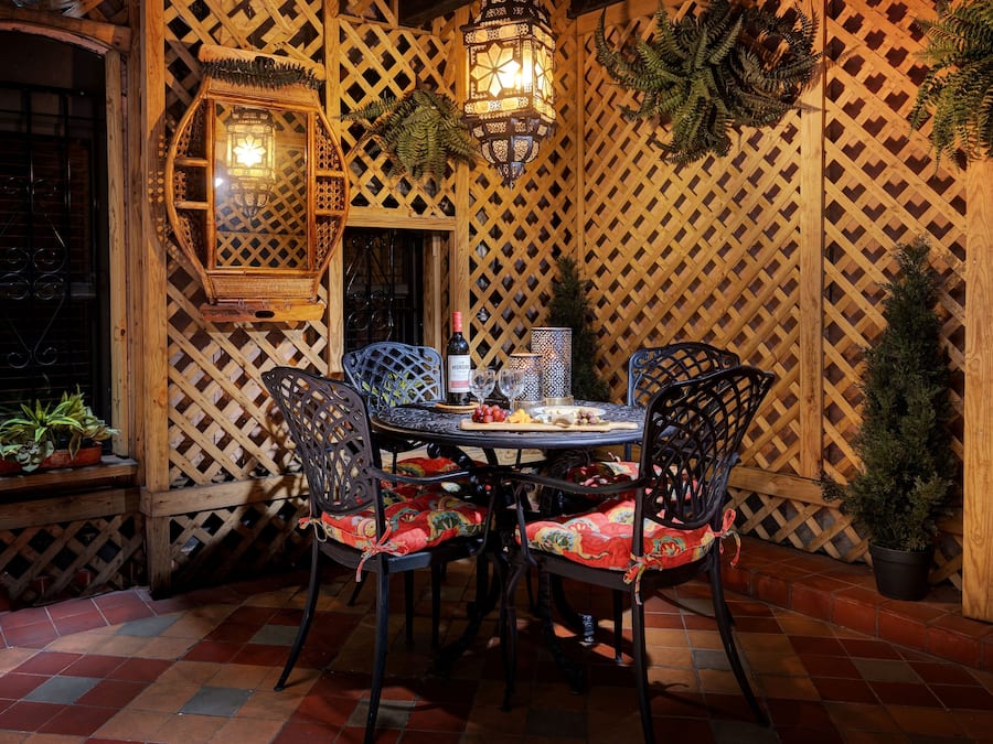 A dining area with a round table, four chairs, and a bottle of wine.