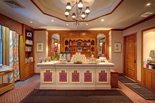 A hotel lobby with a central bar area, a bookshelf, and a reception desk.