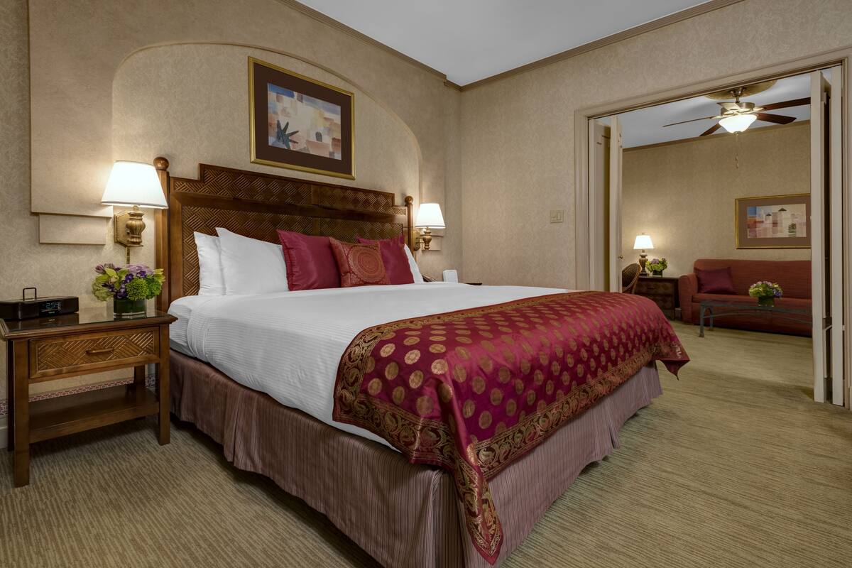 Een hotelkamer met een groot bed, twee nachtkastjes met lampen, een houten hoofdbord en een plafondventilator.