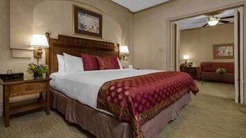 A hotel room with a large bed, two bedside tables with lamps, a wooden headboard, and a ceiling fan.