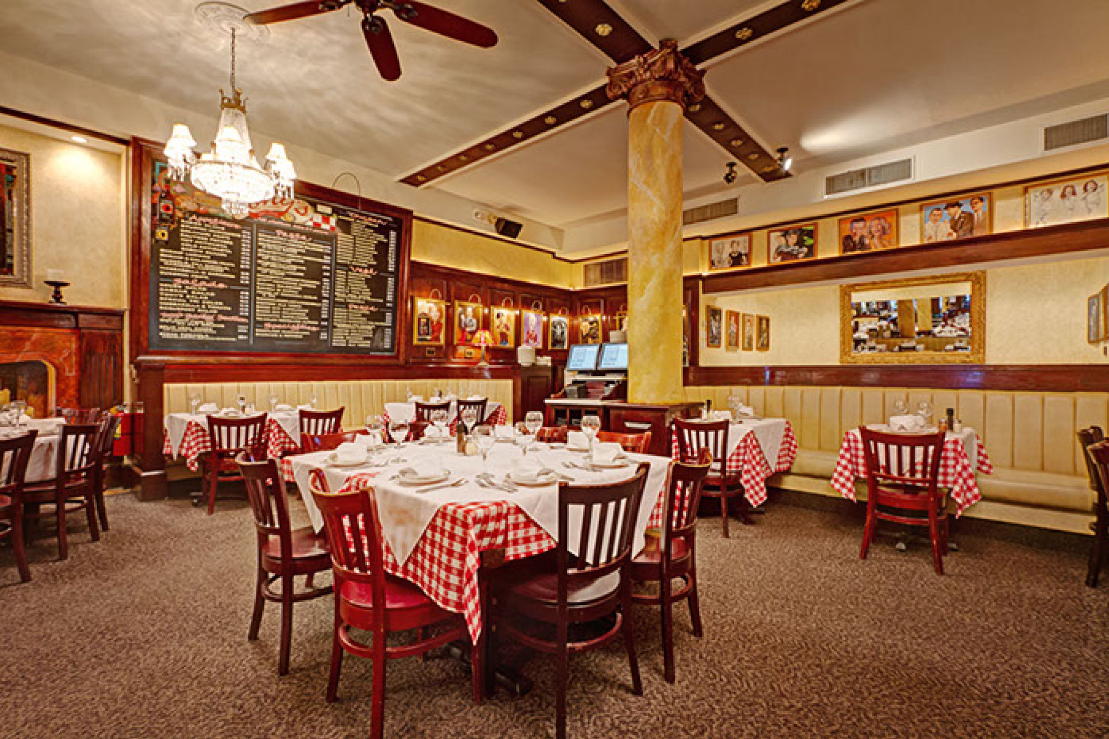 A restaurant with wooden tables and chairs, a chandelier, and a menu board.