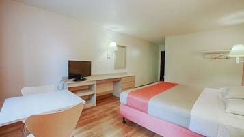 Una habitación de hotel con una cama, un escritorio, una silla, un televisor y un espejo.