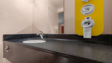 A bathroom with a black granite sink, a mirror, and a yellow towel dispenser with two towels.