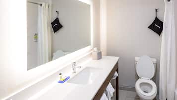 A modern bathroom with a white sink, a mirror, a toilet, and a shower curtain.