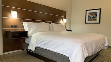 Una habitación de hotel con cama, mesitas de noche, lámparas de pared y un cuadro enmarcado.