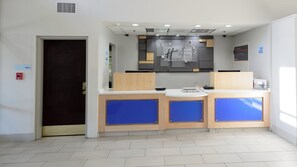 Un comptoir d’accueil doté d’un écran numérique, un système d’alarme incendie et une signalétique indiquant les bureaux.