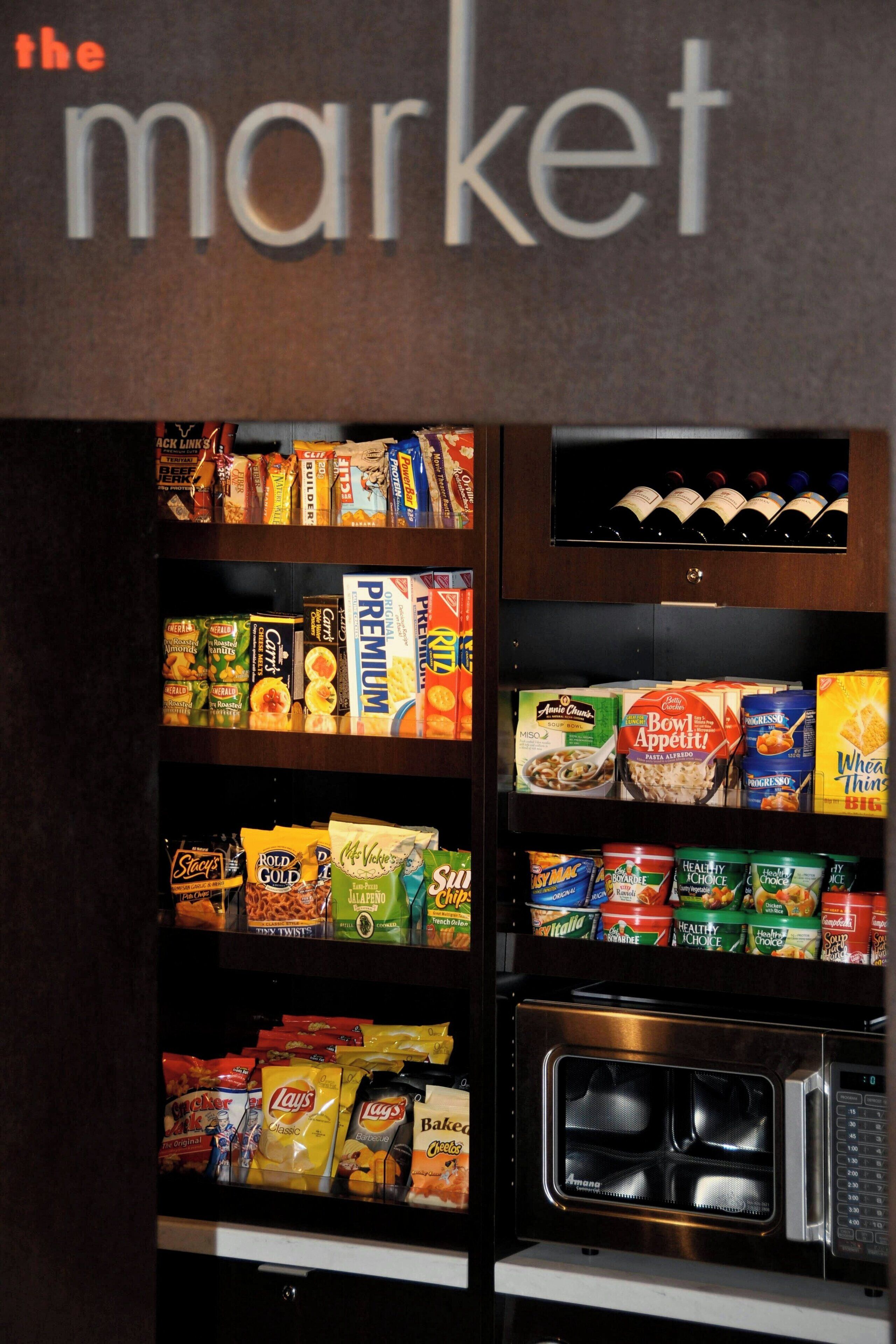 Een automaat gevuld met snacks, drankjes en een magnetron.