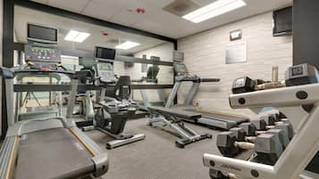 A gym with treadmills, weight machines, and a mirrored wall.