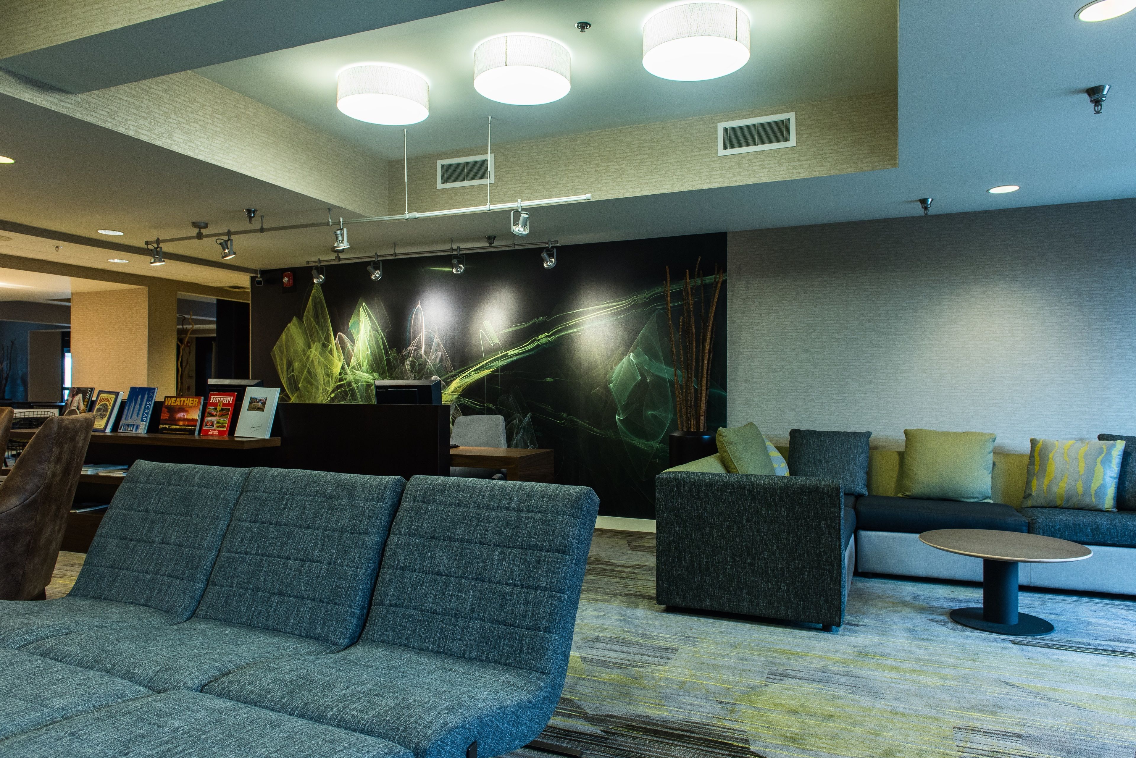 A modern lobby with a sofa, armchairs, a coffee table, and a wall with abstract art.