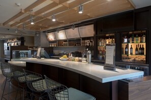 Una zona de bar moderna con una barra curva, taburetes y un panel con la carta.