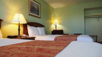 A hotel room with two beds, each with a red and white bedspread, two bedside lamps, a nightstand with a telephone, and a painting on the wall.