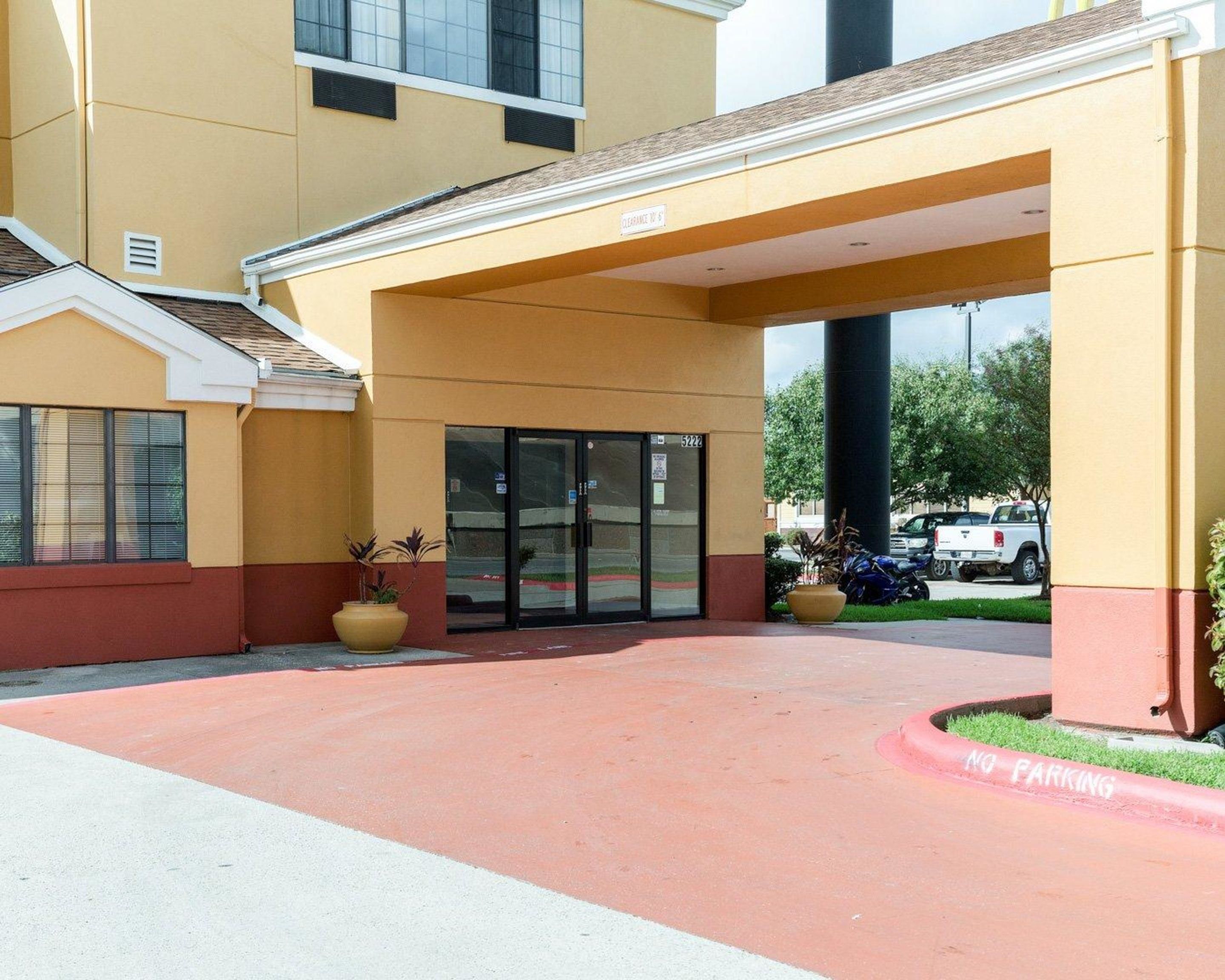 A hotel entrance with a covered walkway, a parking area, and a 'No Parking' sign.