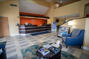 Welcome to the hotel lobby, where guests can check in and relax in the seating area with a comfortable armchair.