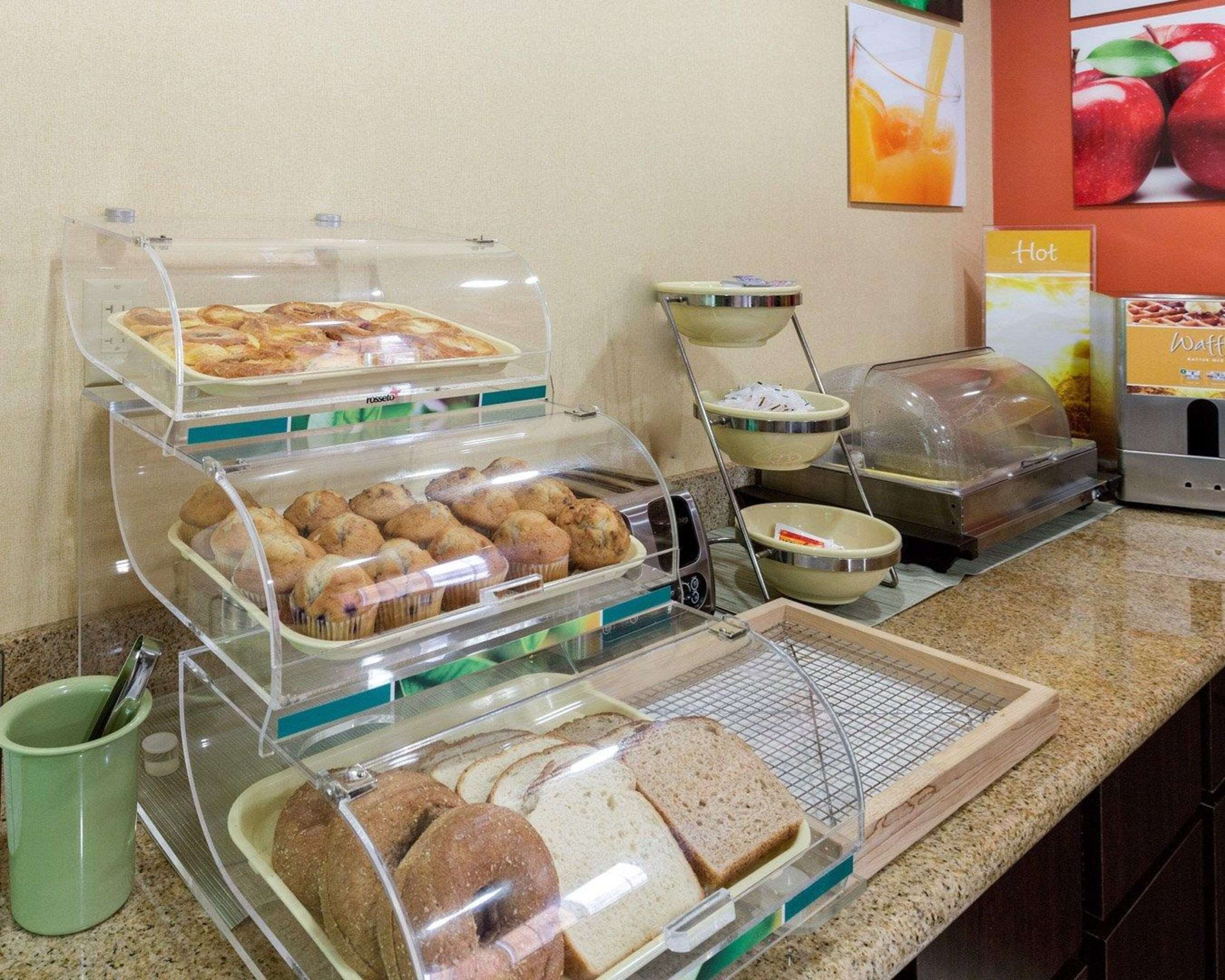 A breakfast buffet with various food items like muffins, pastries, and bread.