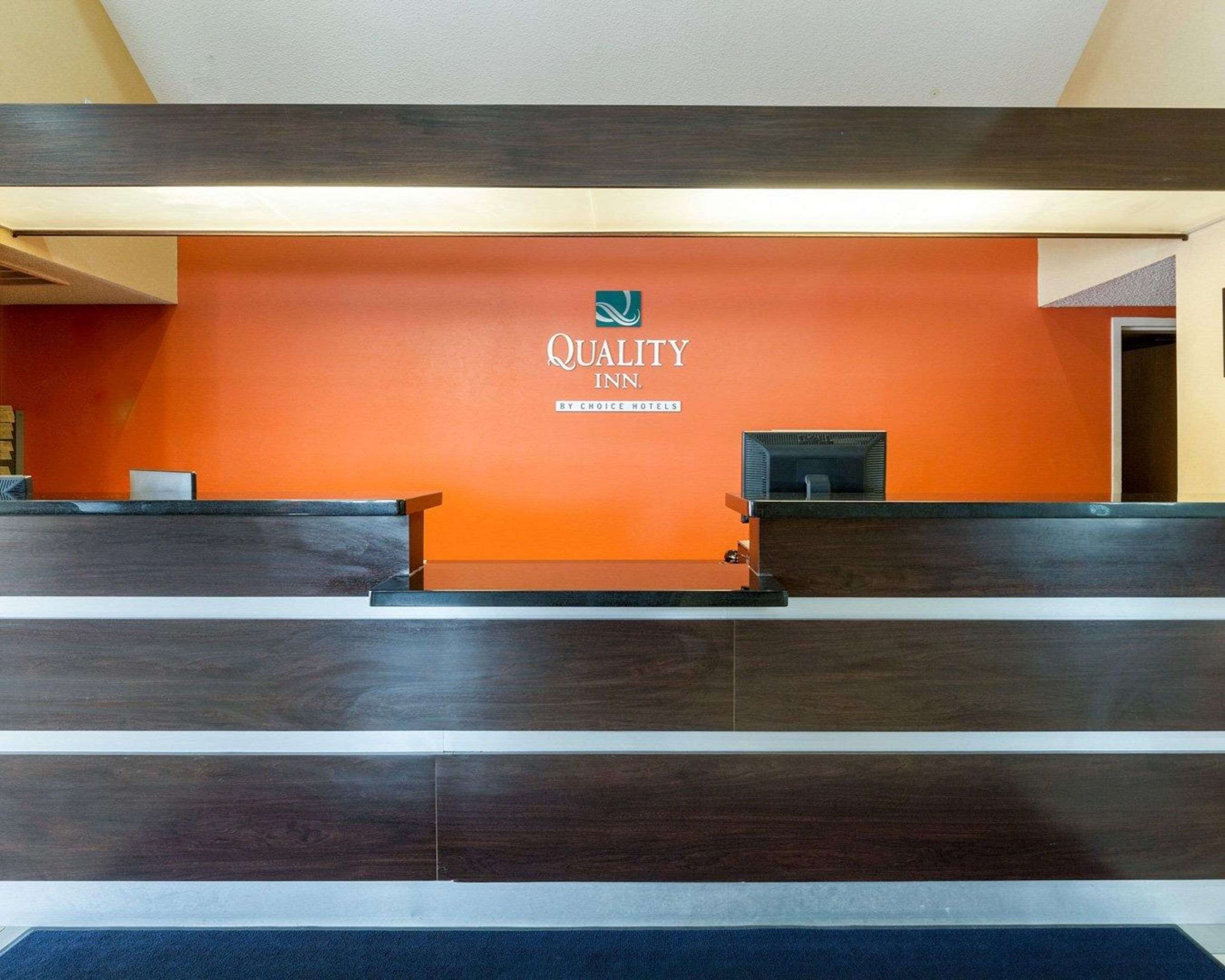A reception desk with a sign that reads "Quality Inn by Choice Hotels."