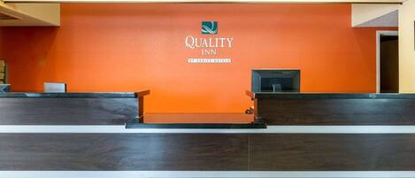 A reception desk with a sign that reads "Quality Inn by Choice Hotels."