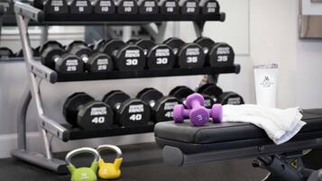 Et fitnessrum med bænk, kettlebells og vægtstangsstativ.
