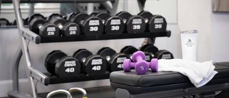 A gym with a bench, kettlebells, and a dumbbell rack.