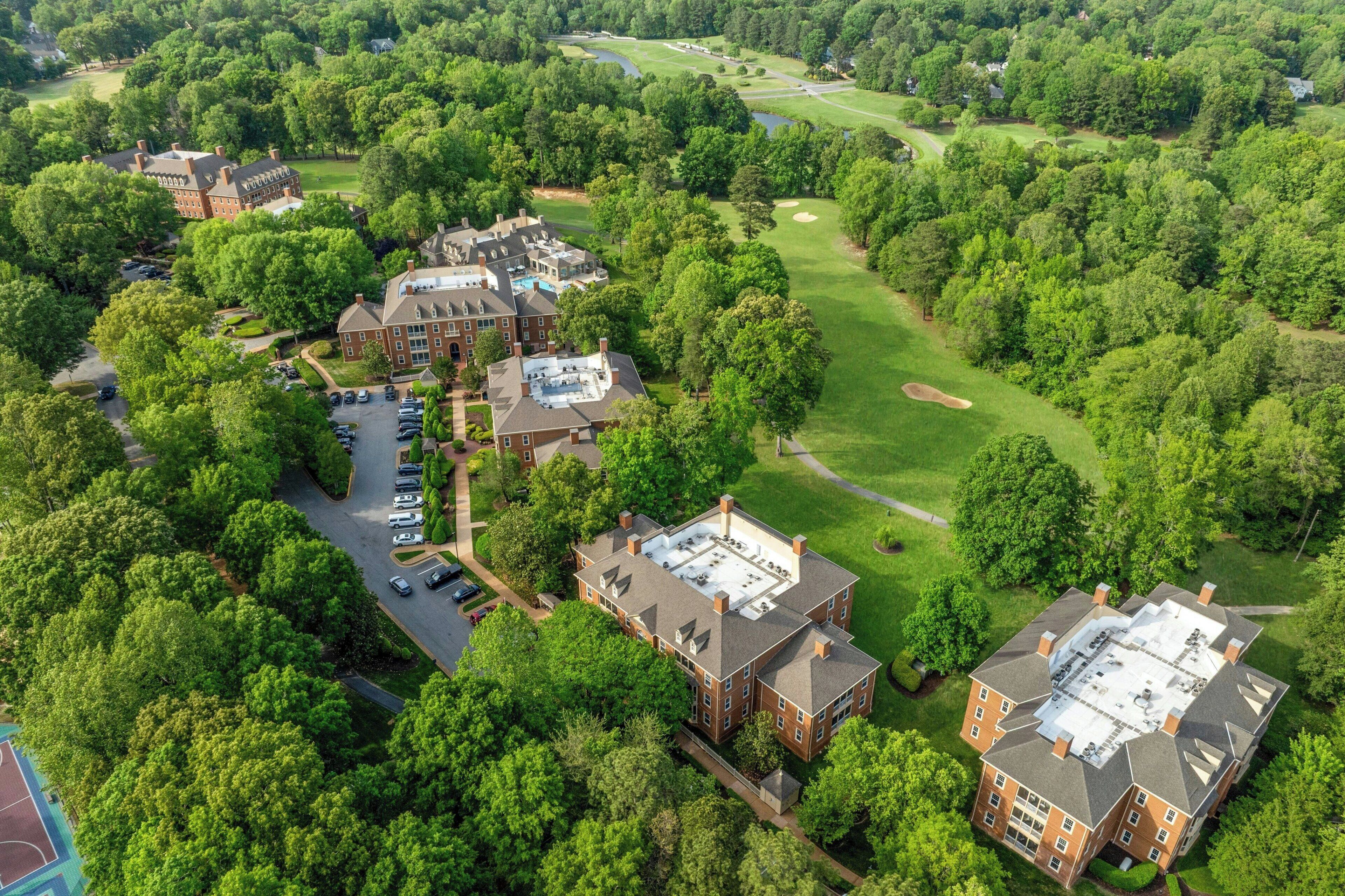 An aerial view of a campus with multiple buildings, a parking lot, and a golf course.