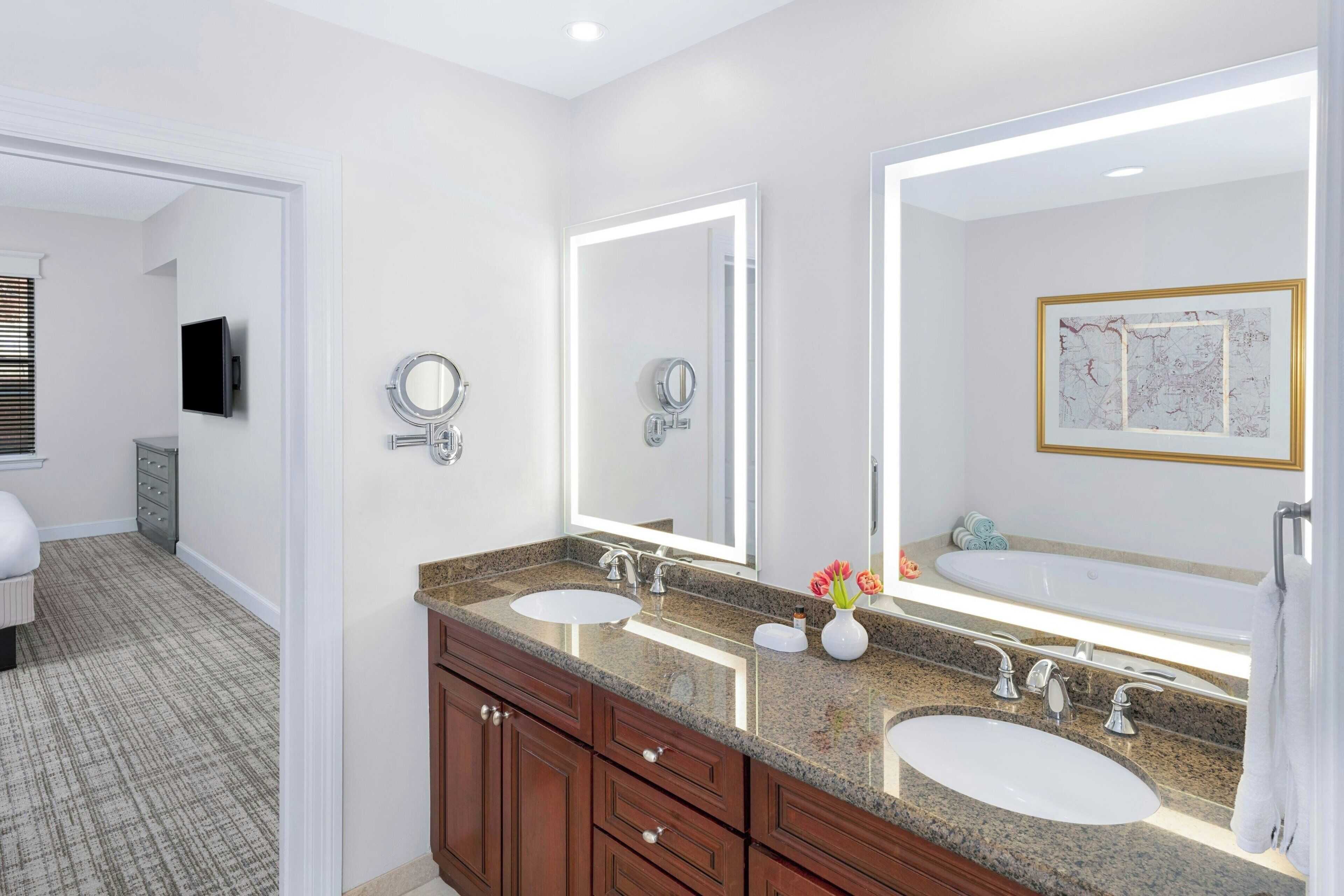 A modern bathroom with two sinks, a large mirror, and a vanity with drawers.