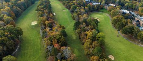 An aerial view of a golf course with multiple bunkers and a clubhouse.