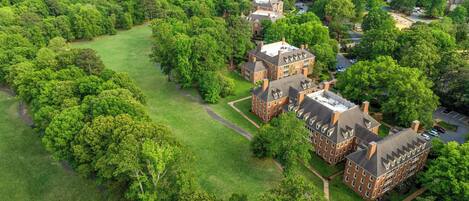 An aerial view of a large estate with multiple brick buildings, expansive green lawns, and dense tree coverage.