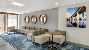 A hotel lobby with a seating area, round mirrors, and a large window. - Best Western PLUS Executive Hotel (Richmond)