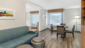 A modern hotel room with a sofa, round table, chairs, a lamp, and artwork on the wall. - Best Western PLUS Executive Hotel (Richmond)