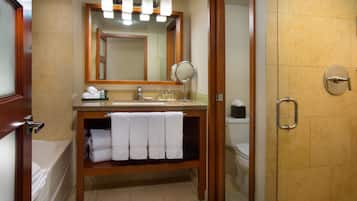 A bathroom with a wooden vanity, a mirror, a sink, and a shower area.