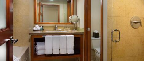 Un baño con tocador de madera, espejo, lavabo y zona de ducha.