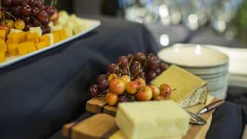 A cheese board with various cheeses and grapes on a wooden cutting board.