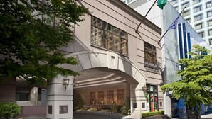A hotel entrance with a curved facade, large windows, and a sign indicating valet parking.