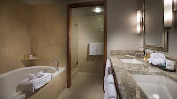 A modern bathroom with a bathtub, two sinks, and a shower.
