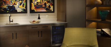 A modern kitchen with a built-in dishwasher, a wine bottle, and two framed paintings on the wall.
