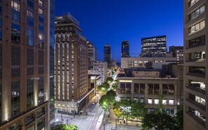 A cityscape at dusk with modern buildings, a prominent Roosevelt Hotel, and a street lined with trees. - The Paramount Hotel (Seattle)